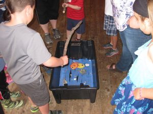 Kids playing a fishing game in a bucket with paper fish.